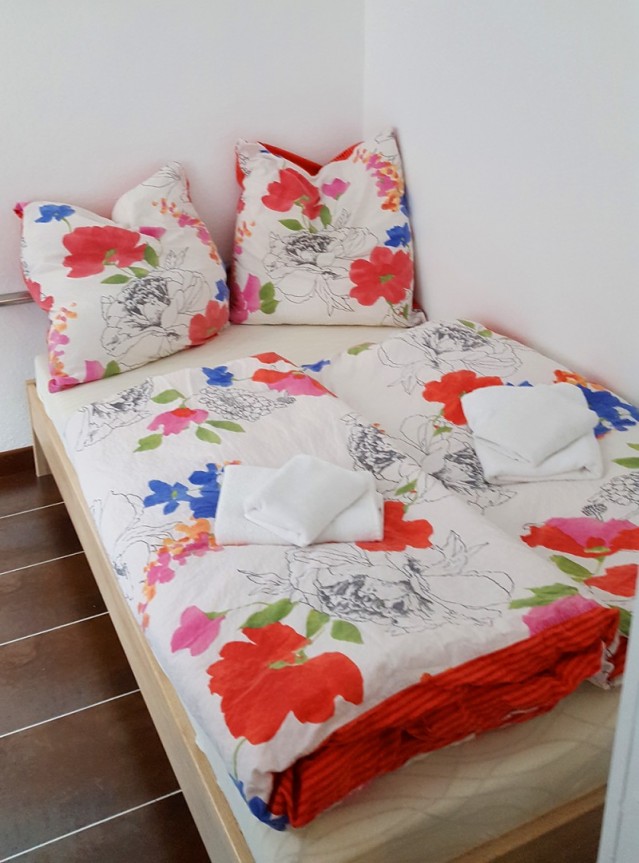 Doppel und Ehe-Bett aus Holz mit frischer Blumen-Bettwäsche und Springfedermatratze.